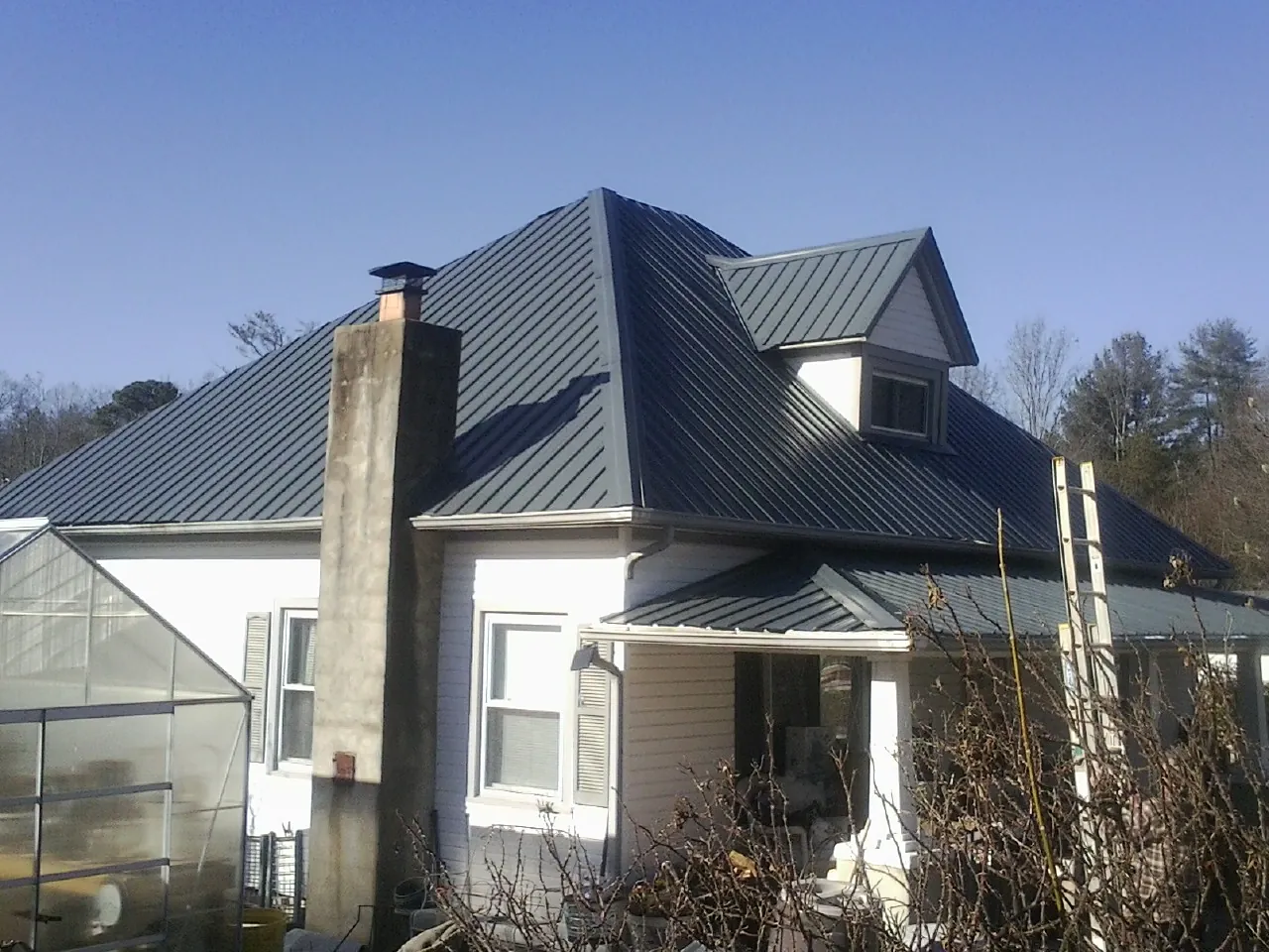 Dark blue standing seam metal roof on a white farmhouse with dormer — Slate & Tile Roof Repair by Roofing Brothers in Allentown