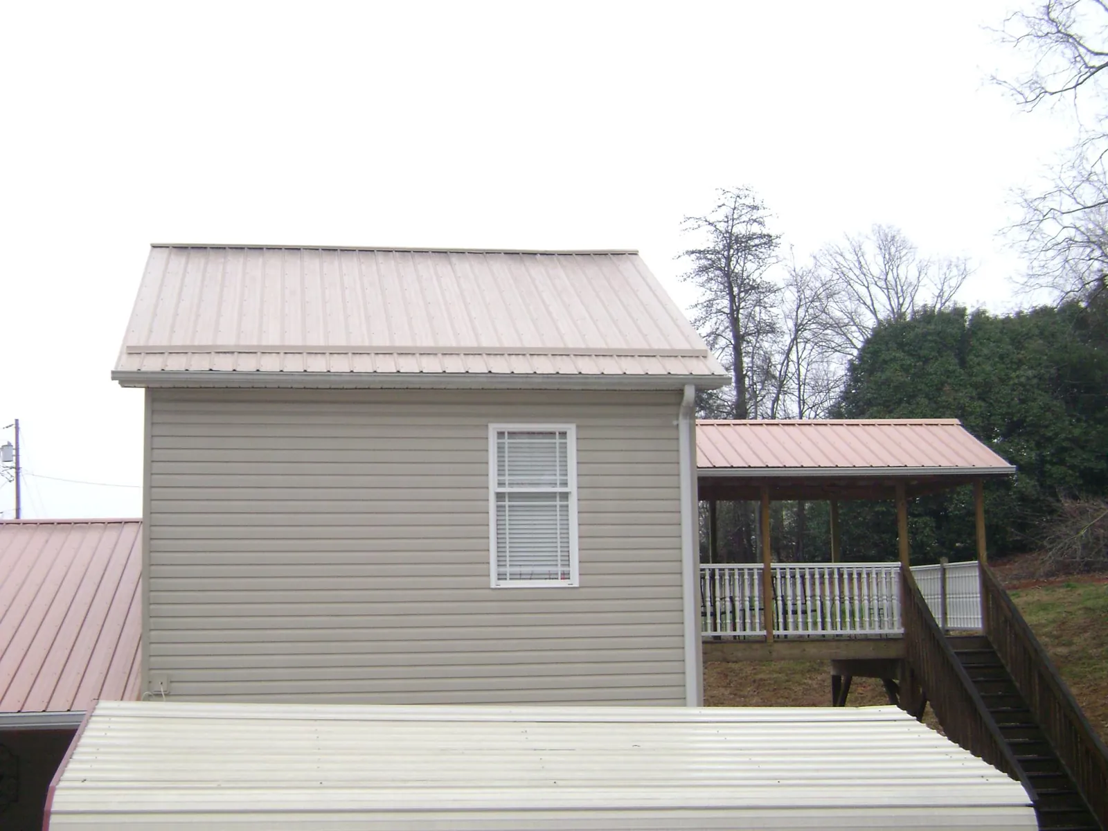 Tan metal roofs on a two story addition and attached porch, from a Roof Replacement job in Allentown