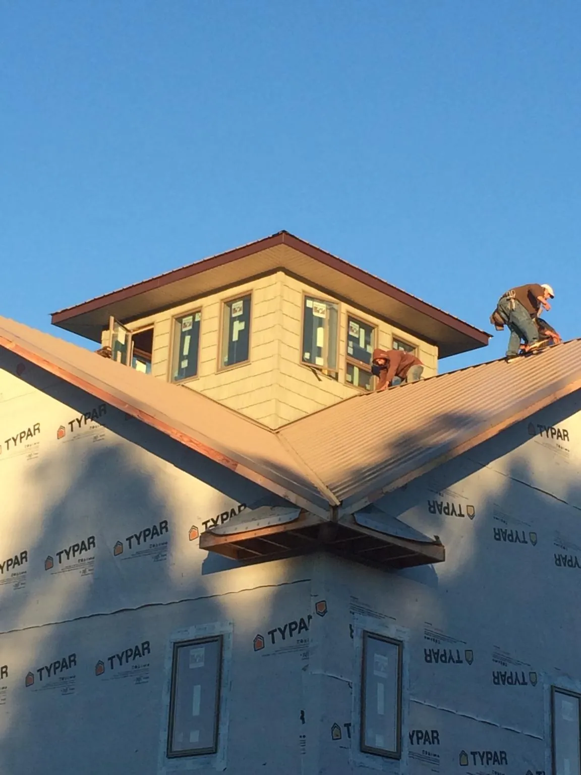 Roofers working around a rooftop cupola on a new metal roof at sunset — Roof Waterproofing in Allentown by Roofing Brothers